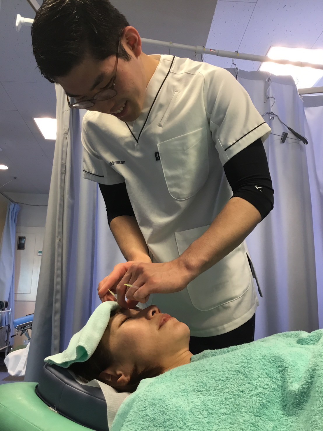 京王八王子院で、花粉症に悩む女性の顔まわりに鍼施術を行うスタッフ。笑顔で丁寧に施術し、鼻づまりや目のかゆみの緩和を目指す様子