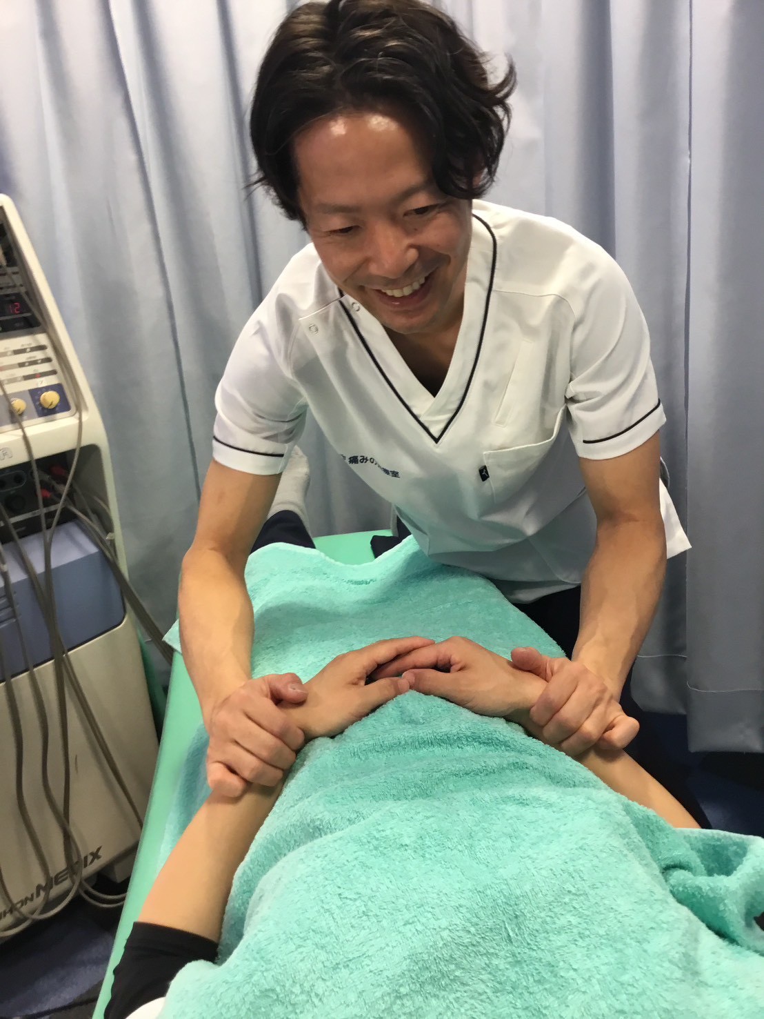 京王八王子院で、花粉症ケアの一環として手元のツボを刺激している施術風景。笑顔のスタッフが丁寧に対応し、自律神経を整える施術中の様子。