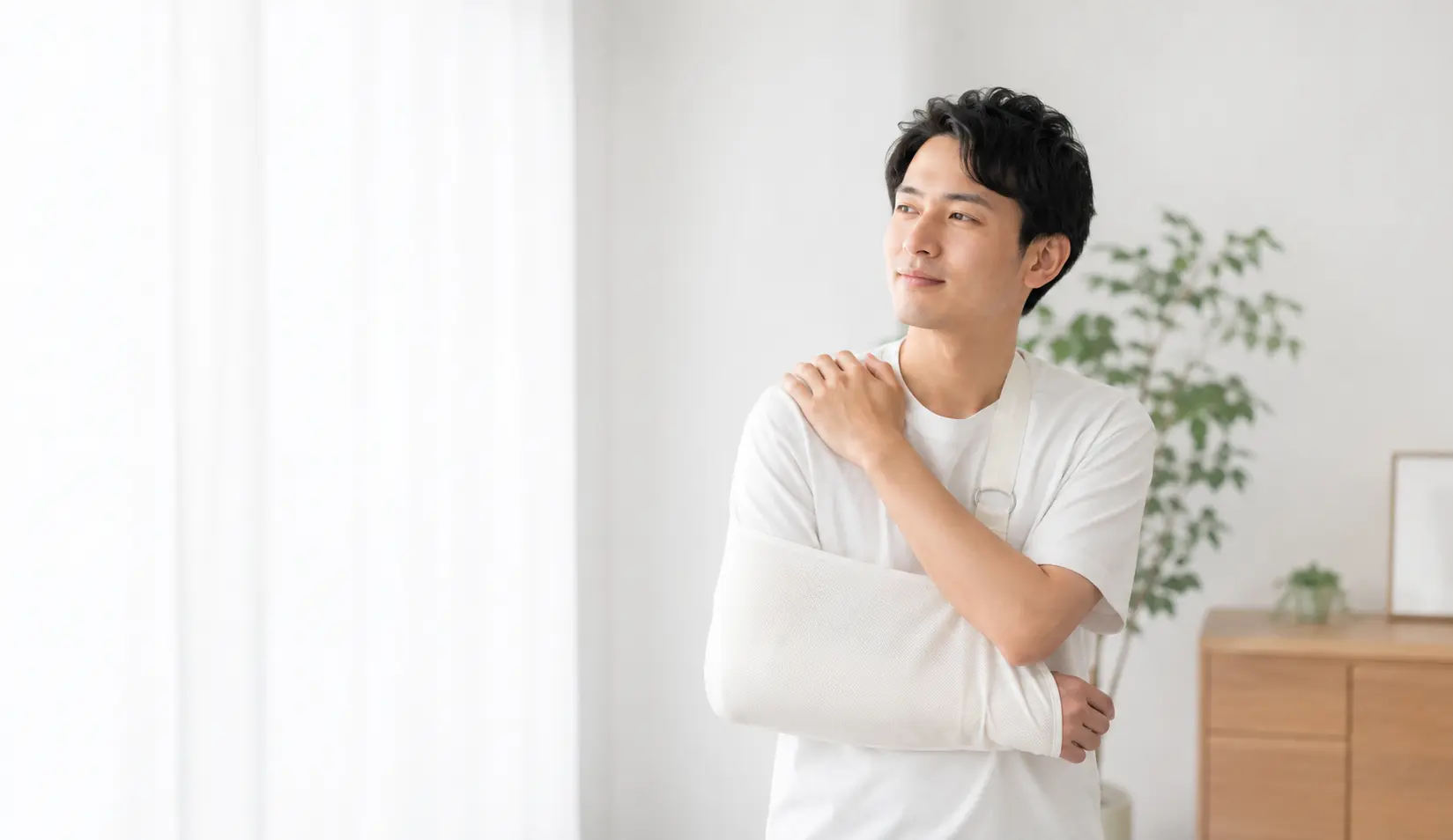 鎖骨骨折後に腕を固定し、肩や鎖骨周辺の状態を確認する男性