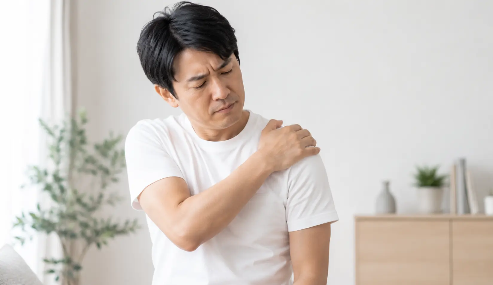 肩に痛みを感じ、つらそうに肩を押さえる男性