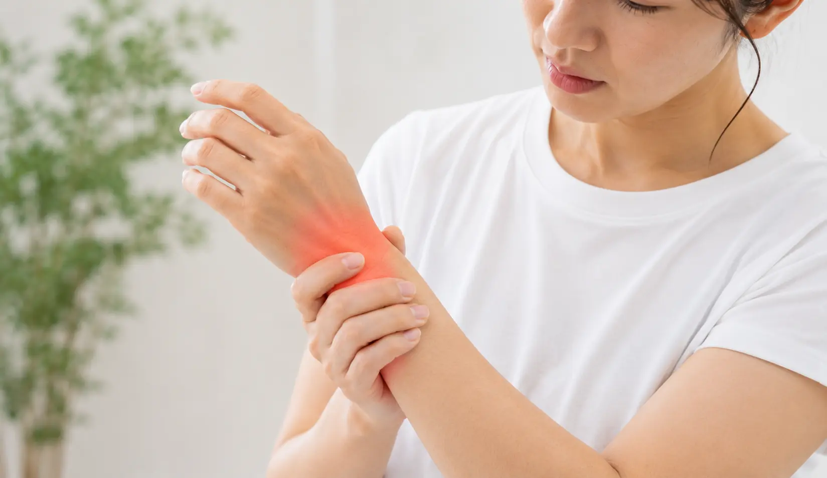 手首の親指側から前腕にかけて痛みを感じ、患部を押さえている女性のイメージ