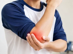 野球肘による離断性骨軟骨炎が疑われる肘の外側の痛みを、反対の手で押さえている様子